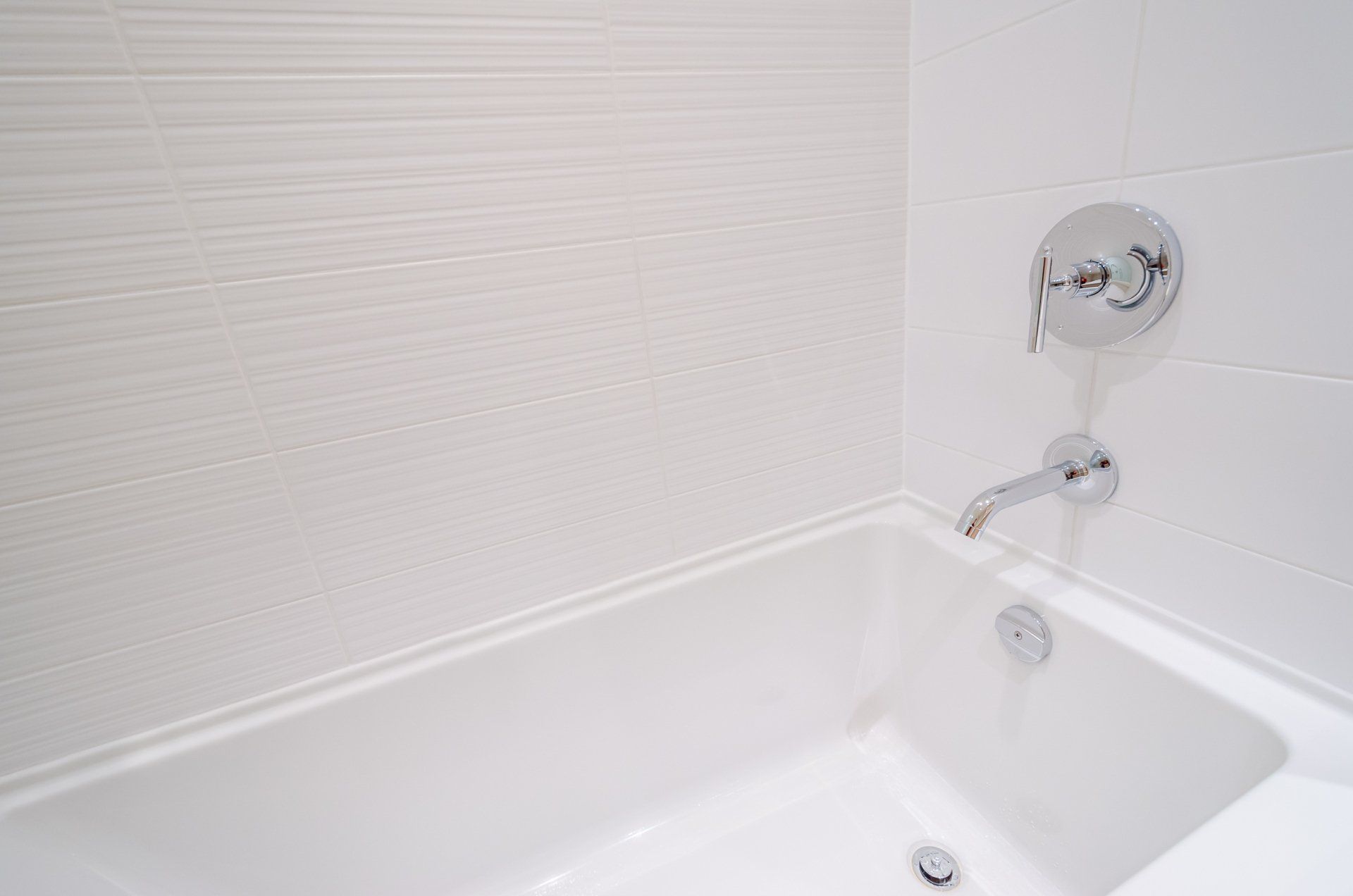 A white bathtub with a chrome shower head in a bathroom